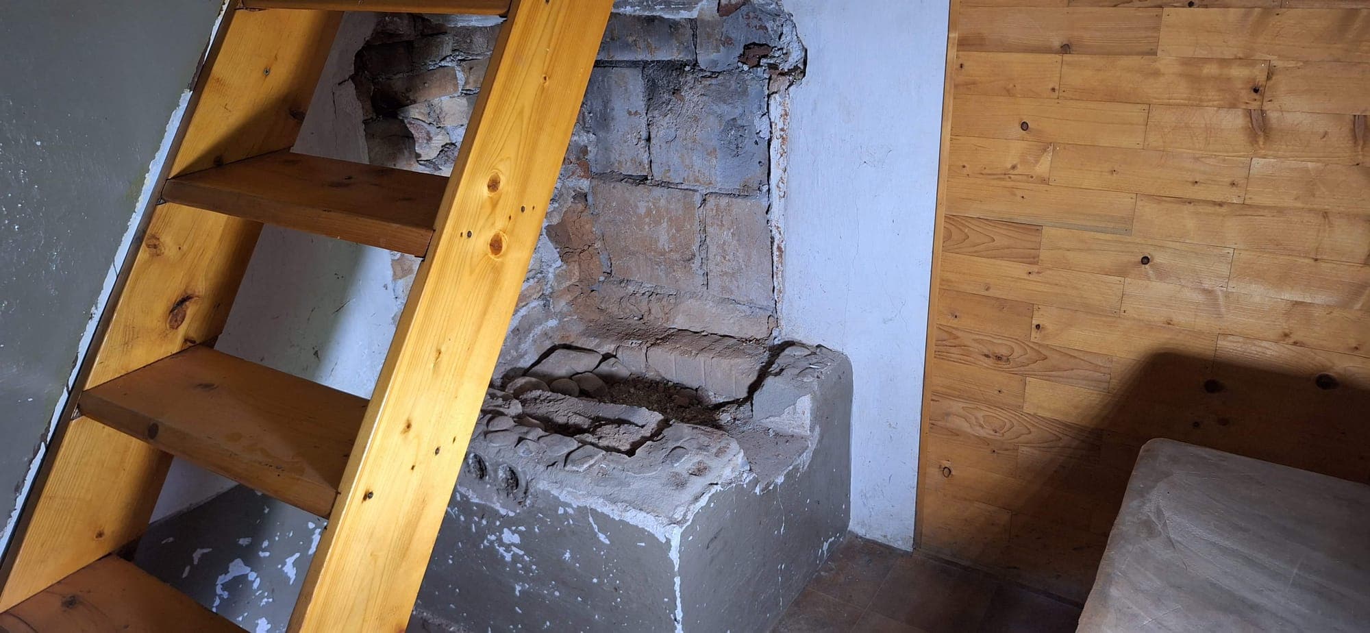Rozpadnutá pôvodná pec pri drevených schodoch na poschodie