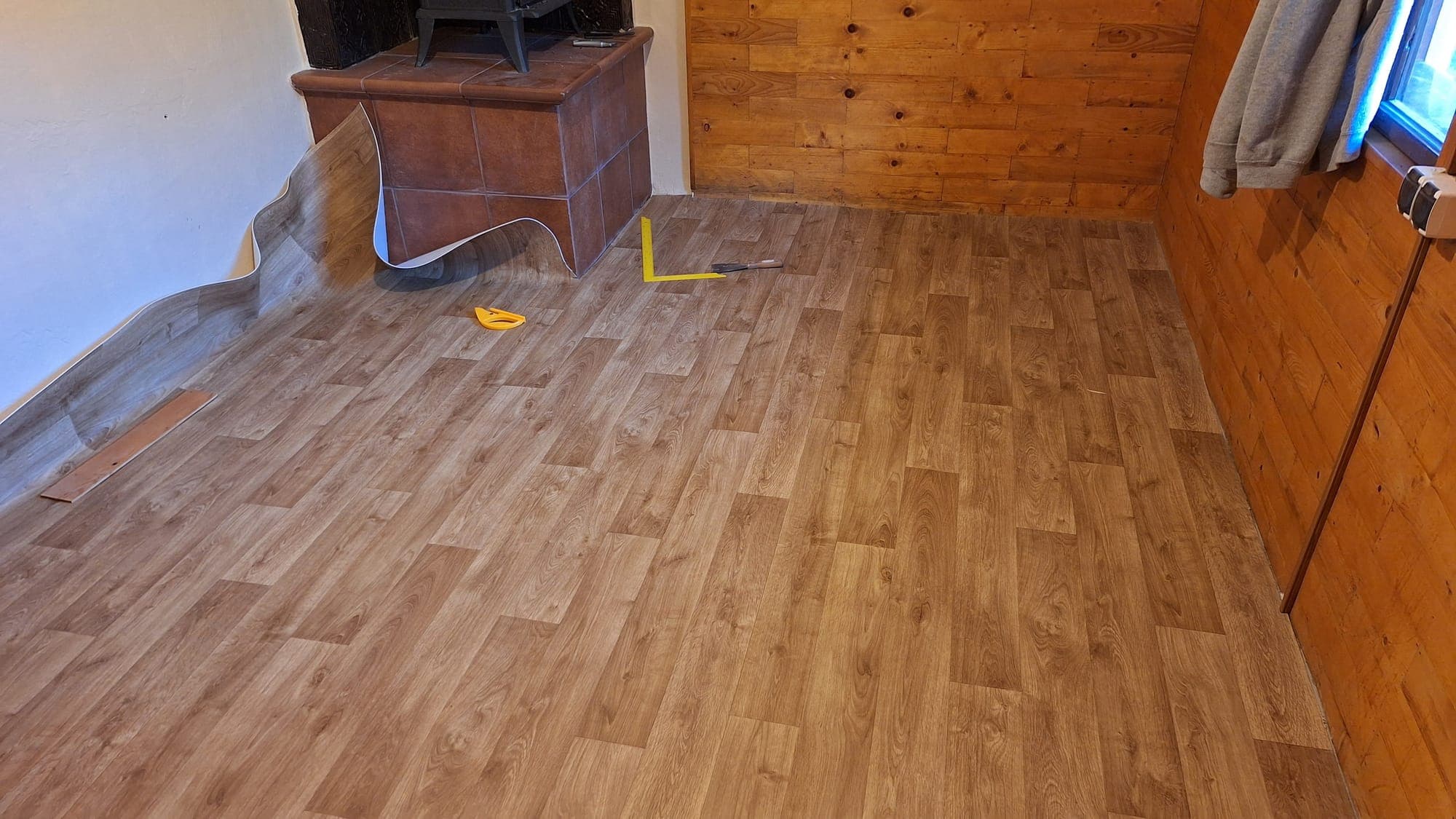 Nová podlaha s dekorom dreva v prízemí, v rohu piecka