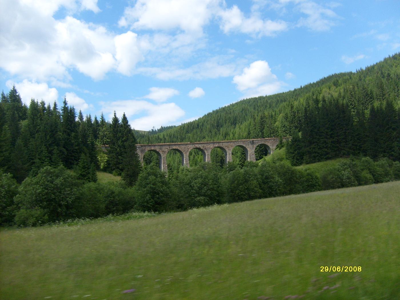 Kamenný železničný viadukt v zelenom údolí pod lesom