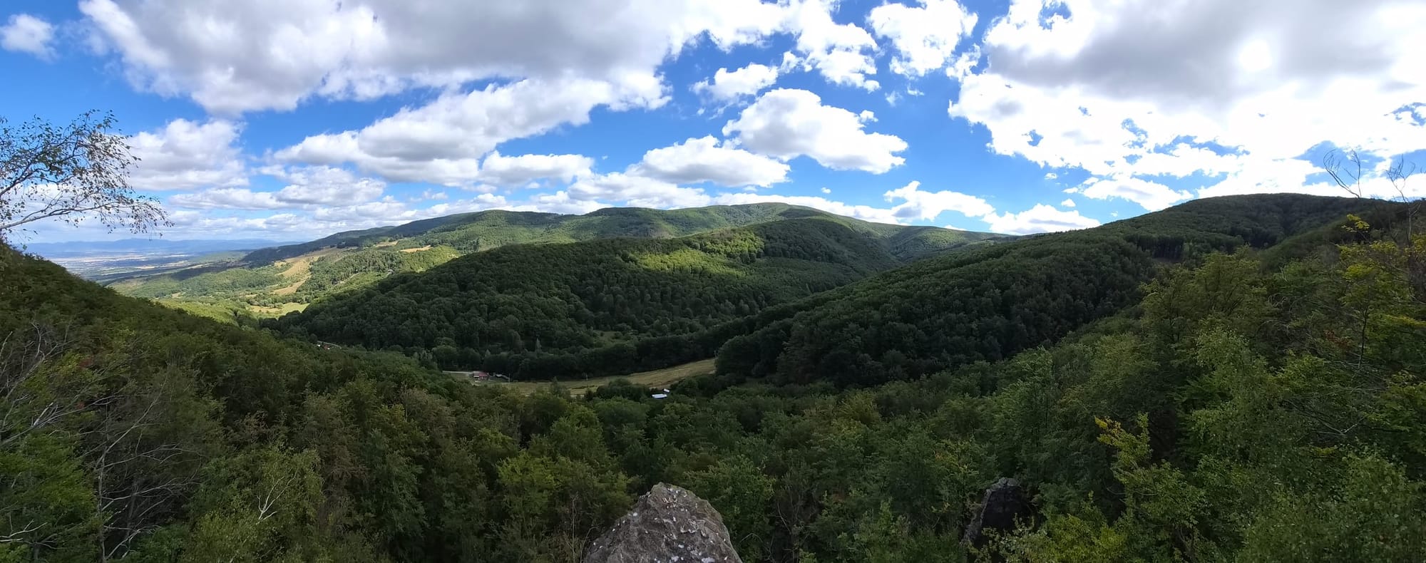 Výhľad z Volkovho zuba na zalesnené kopce Baškovej doliny pod oblačnou oblohou